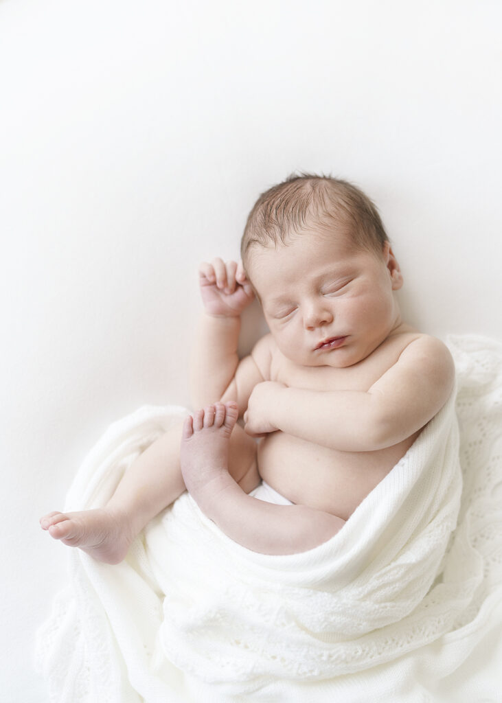 newborn baby boy photographed wrapped in white on a white background