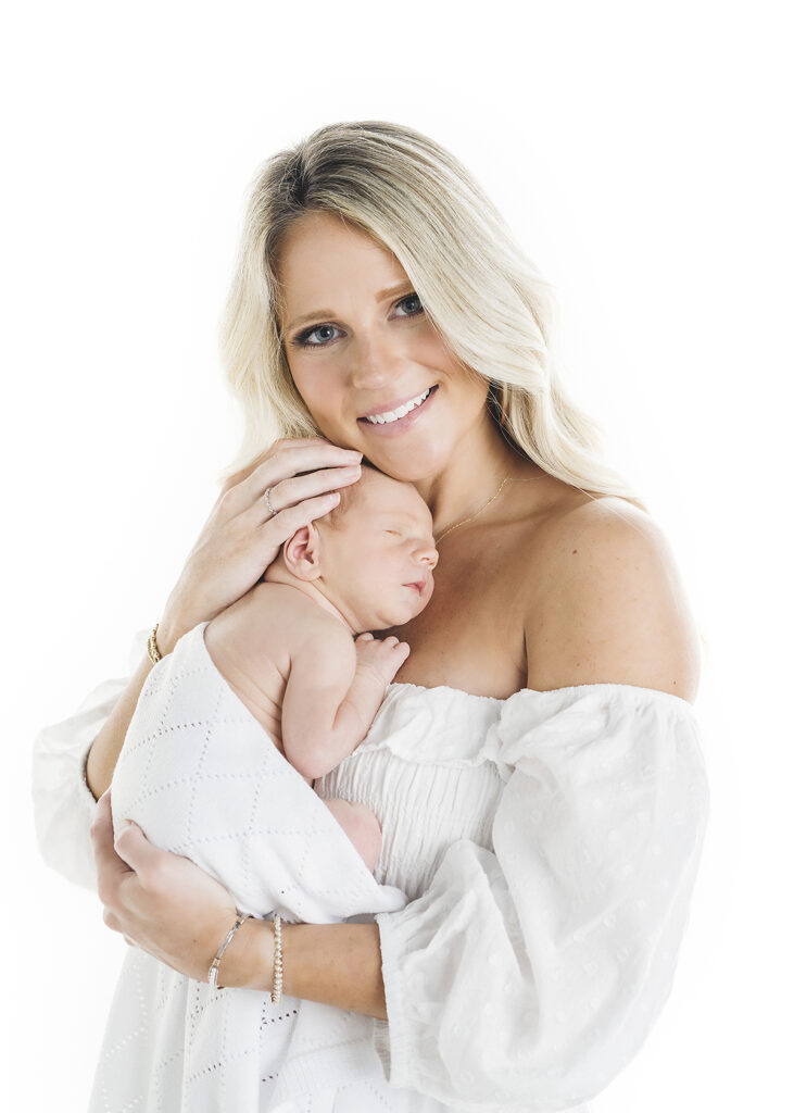 mother in a white dress holding newborn at a studio newborn session in st simons island ga