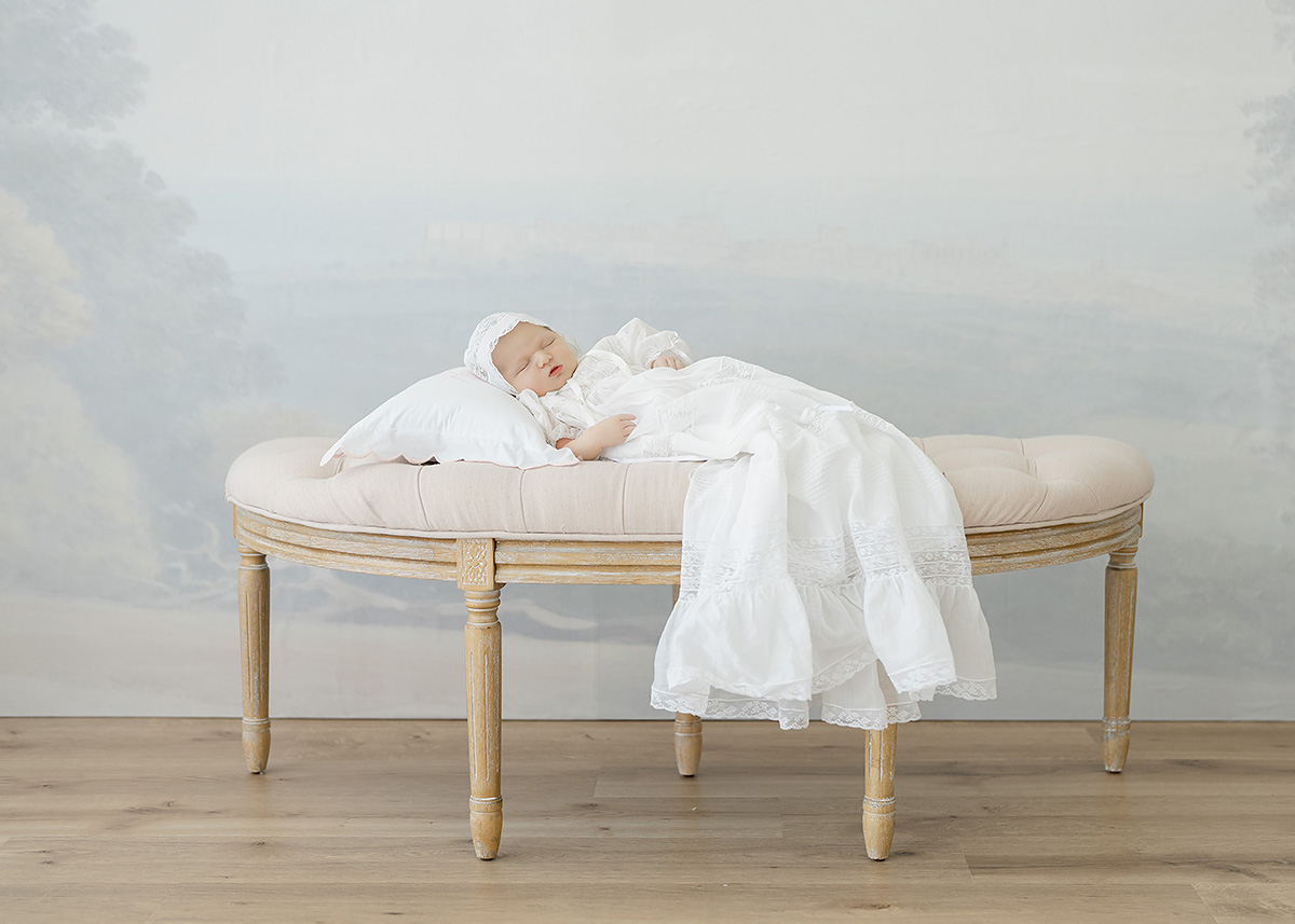 newborn baby photographed in christening gown again studio backdrop
